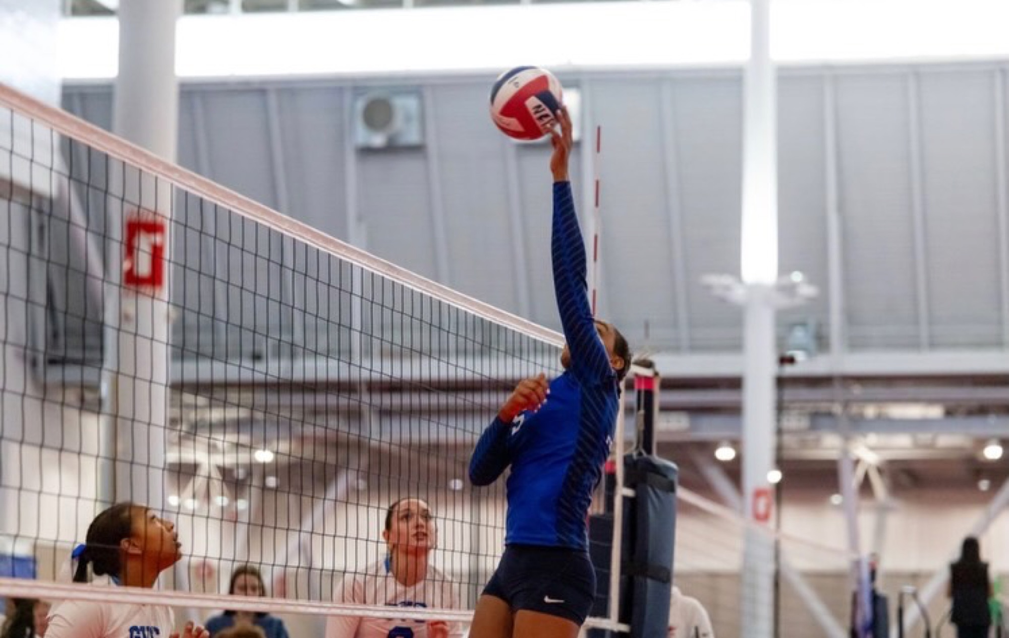 Lia reaches above the net during club competition